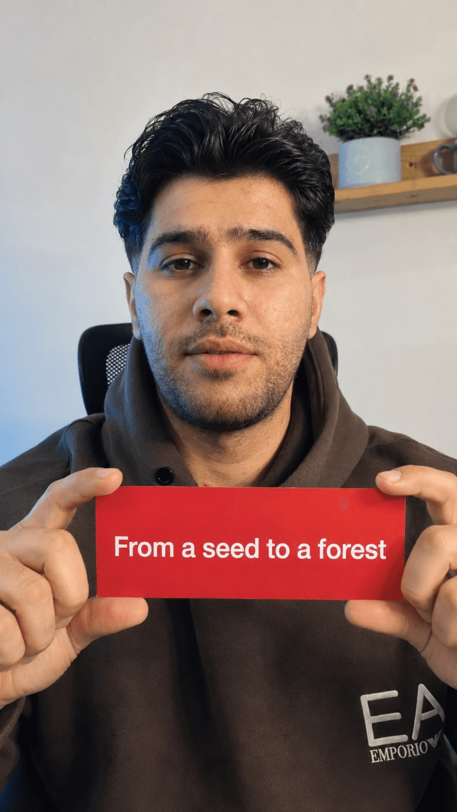 A person holding a red card that reads From a seed to a forest